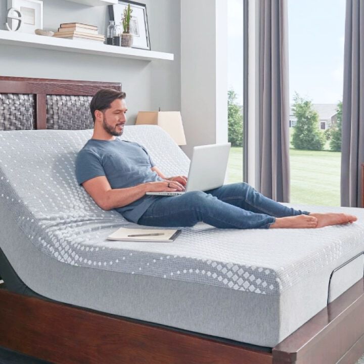 Hombre acostado en colch&oacute;n trabajando en una computadora