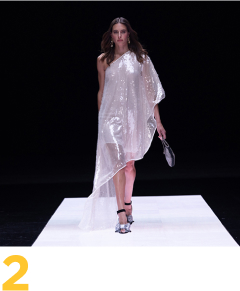 imagen de unas mMujer posando en pasarela, lleva vestido blanco 