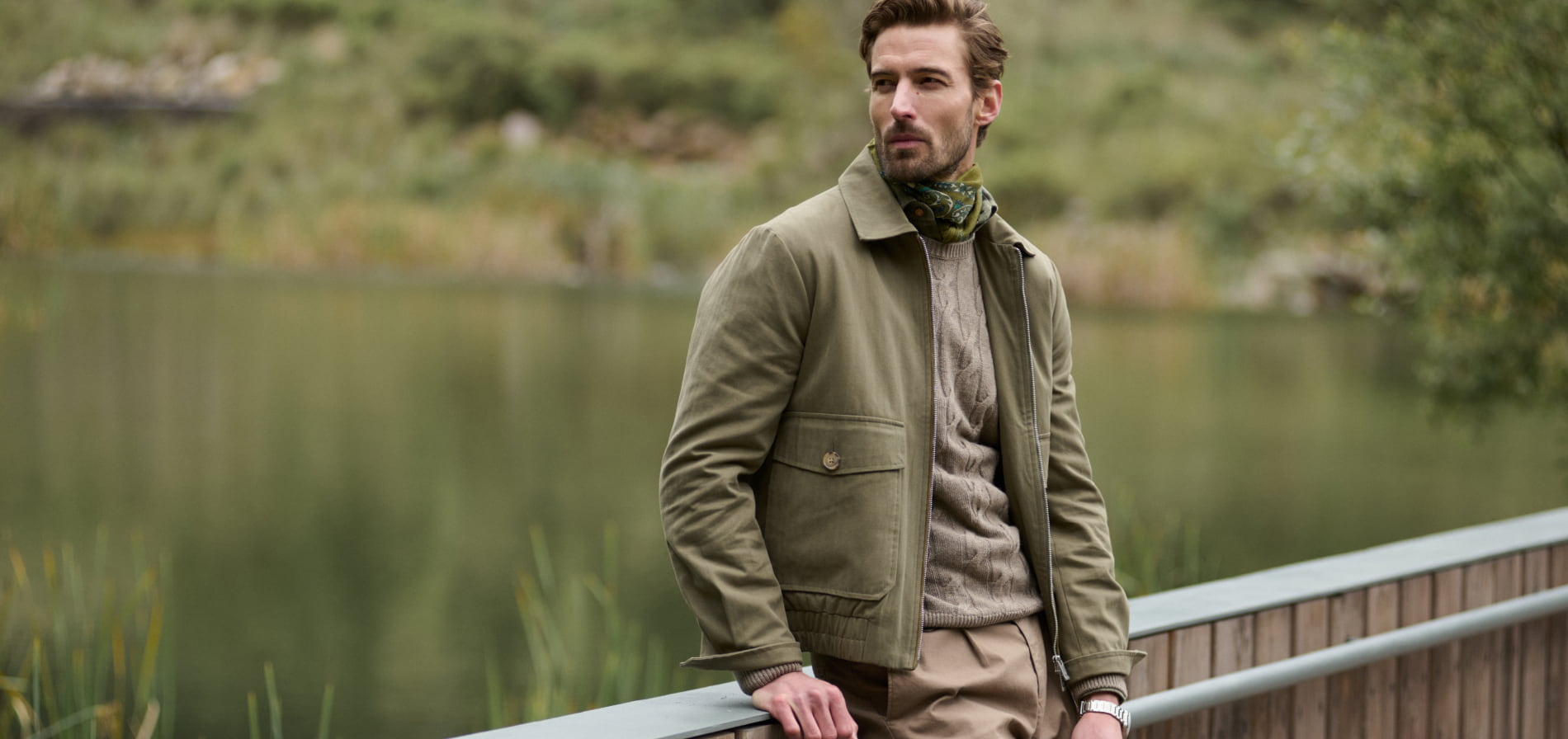 Hombre recargado en un barandal lleva ropa abrigadora color verde