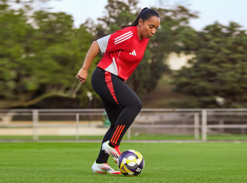 Mujer practicando futbol con uniforme rojo con negro