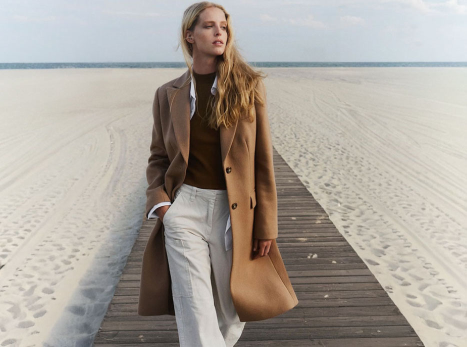 Mujer usando blusa cafe, pantalon blanco y gabardina color cafe CALVIN KLEIN