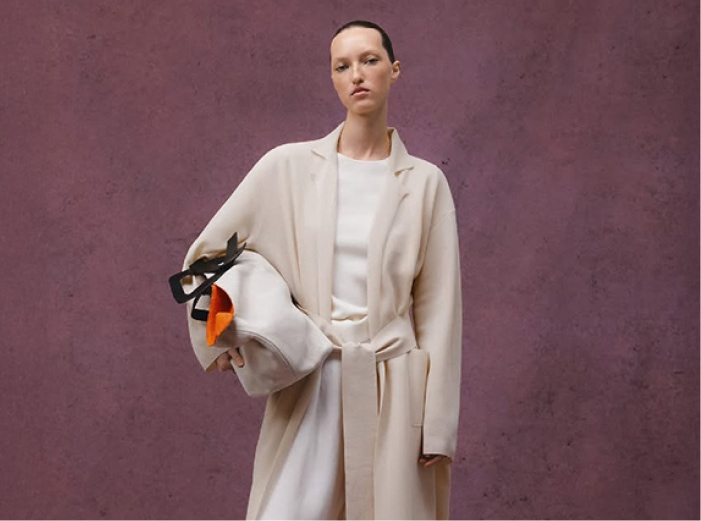 Mujer usando blusa, pantalon blanco y gabardina beige