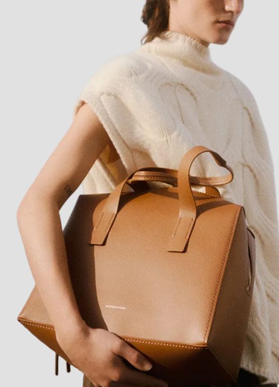 Mujer usando sueter color hueso, lleva un bolso color cafe