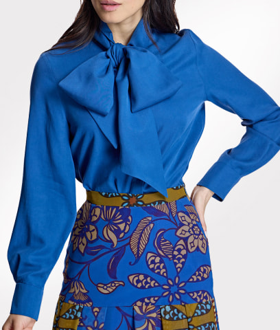 Mujer usando blusa azul marino y falda azul con estampado de ojas cafes