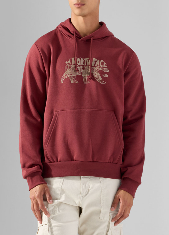 Hombre usando sudadera color roja y pantalon blanco THE NORT FACE