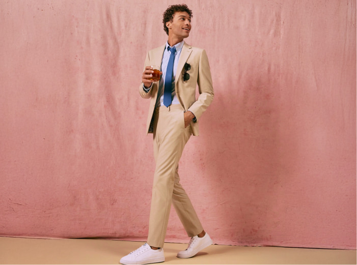 Hombre usando traje color beige con camisa azul clara y corbata azul fuerte