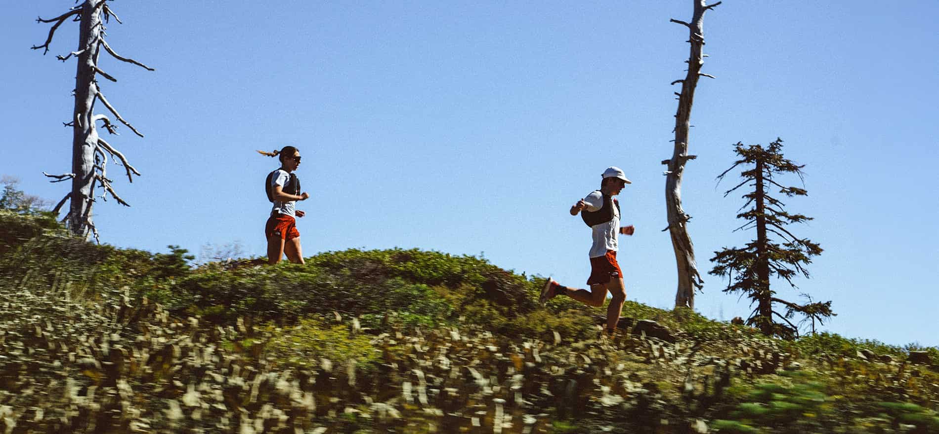Imagen de un hombre y una mujer bajando por un bosque, llevan playera blanca y short rojo  THE NORTH FACE