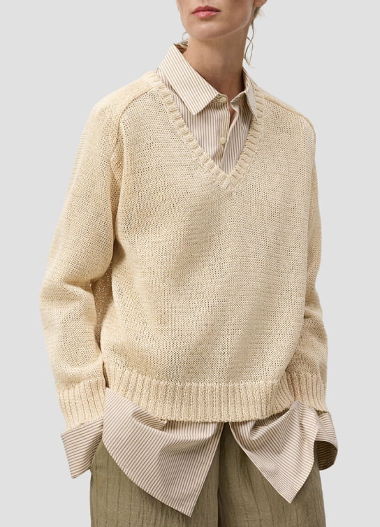 Mujer usando blusa beige sueter color hueso y pantalon verde