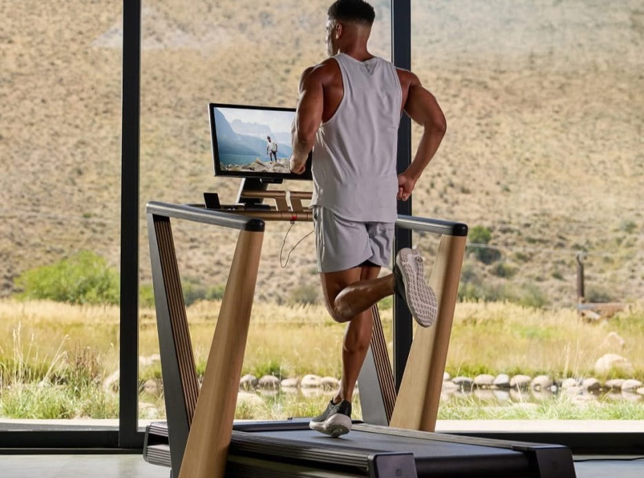 hombre con ropa deportiva haciendo ejercicio en su casa con una caminadora 
