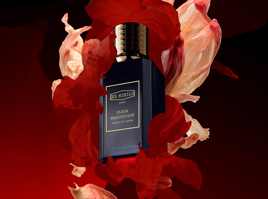 Botella de perfume elegante Ex Nihilo rodeada de p&eacute;talos rojos flotando