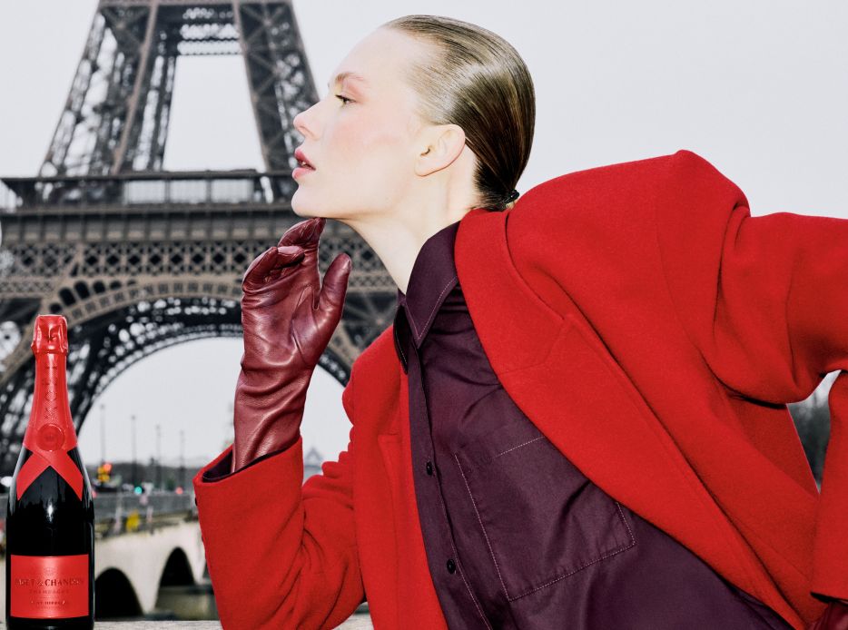 Mujer vestida de rojo junto a una botella de moet en paris