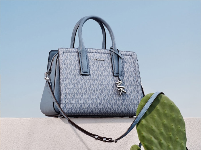 Imagen de un bolso color azul con el monograma de la marca en todo el bolso MICHAEl KORS