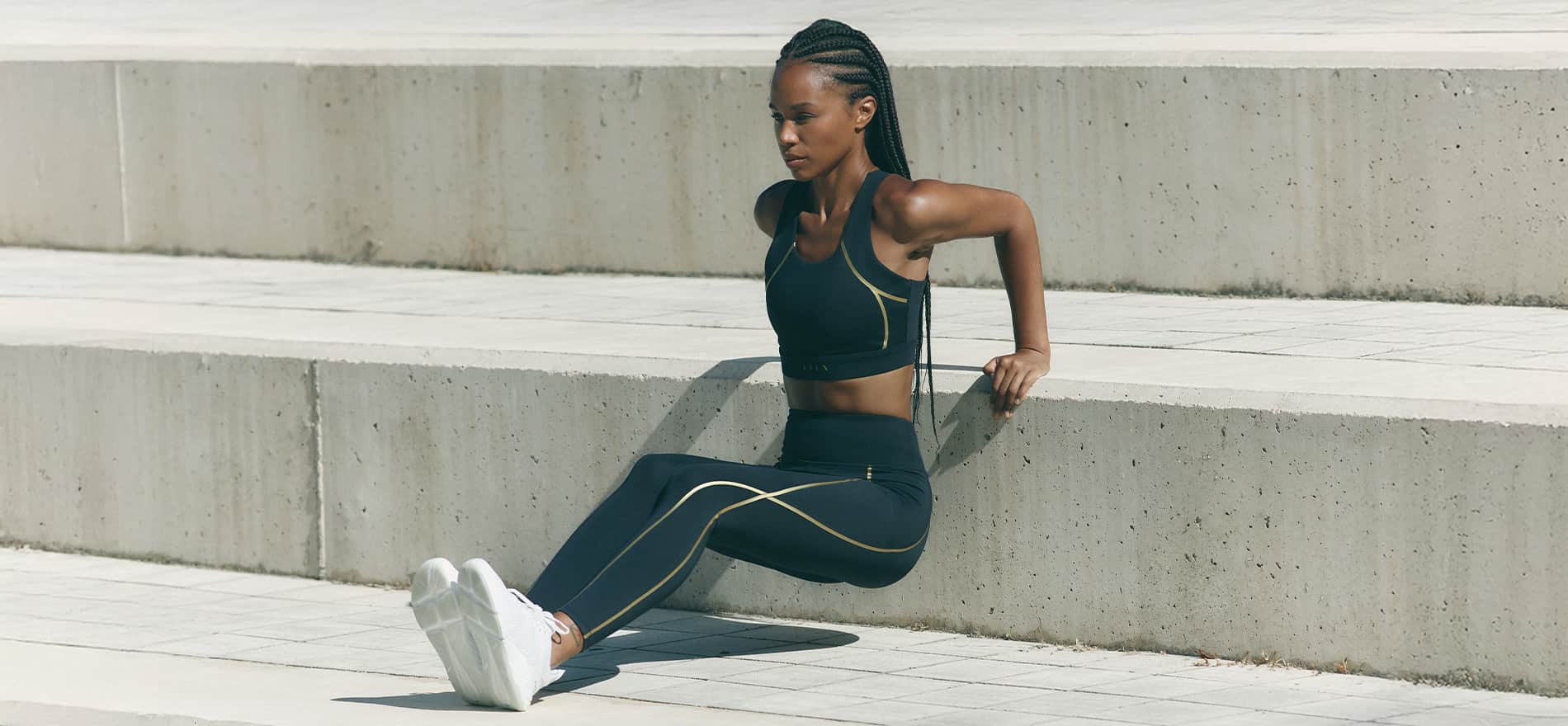Mujer haciendo ejercicio en unas escaleras con ropa deportiva verde YOGA