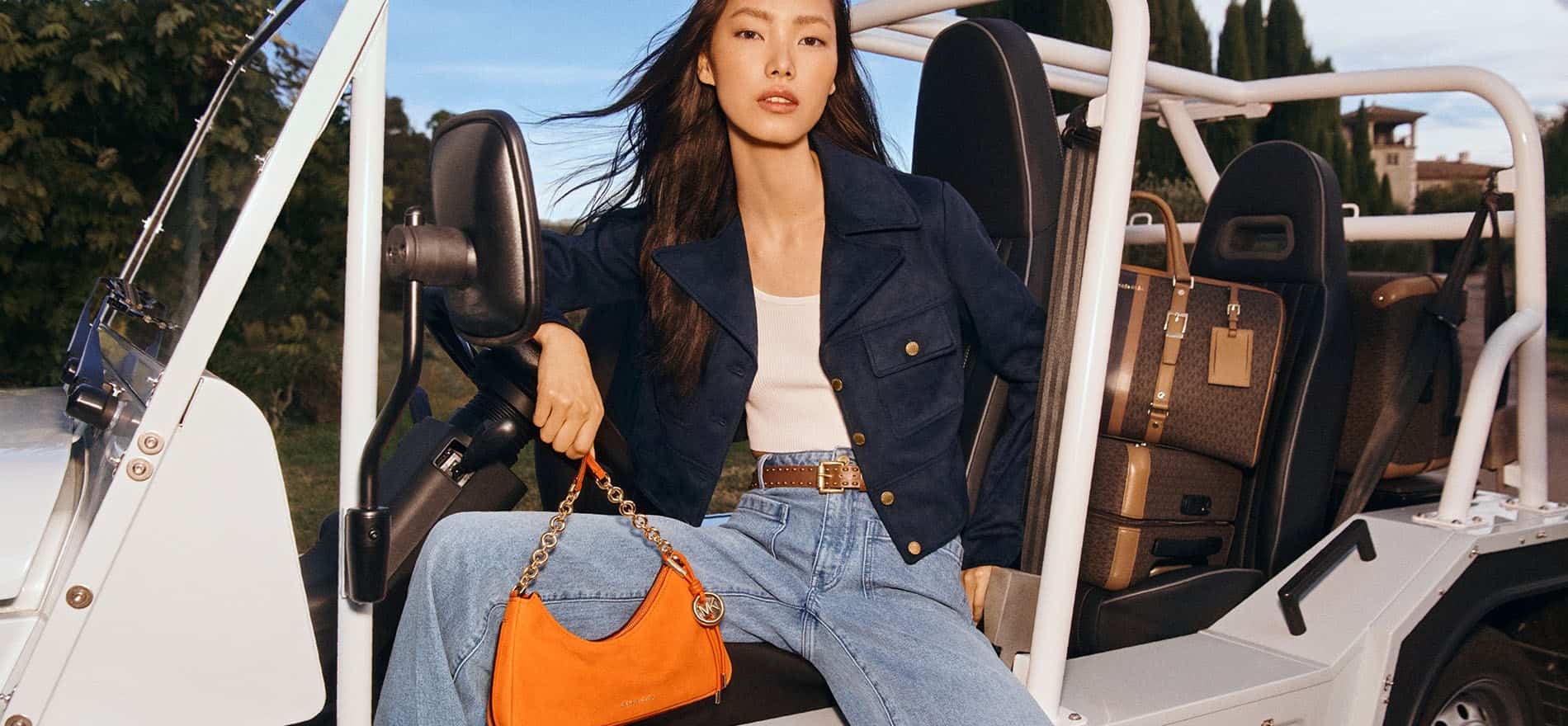 Mujer usando ropa y un bolso naranja de la marca MICHAEL KORS
