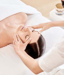 Imagen de una mujer recostada a la cual le realizan un masaje en el rostro