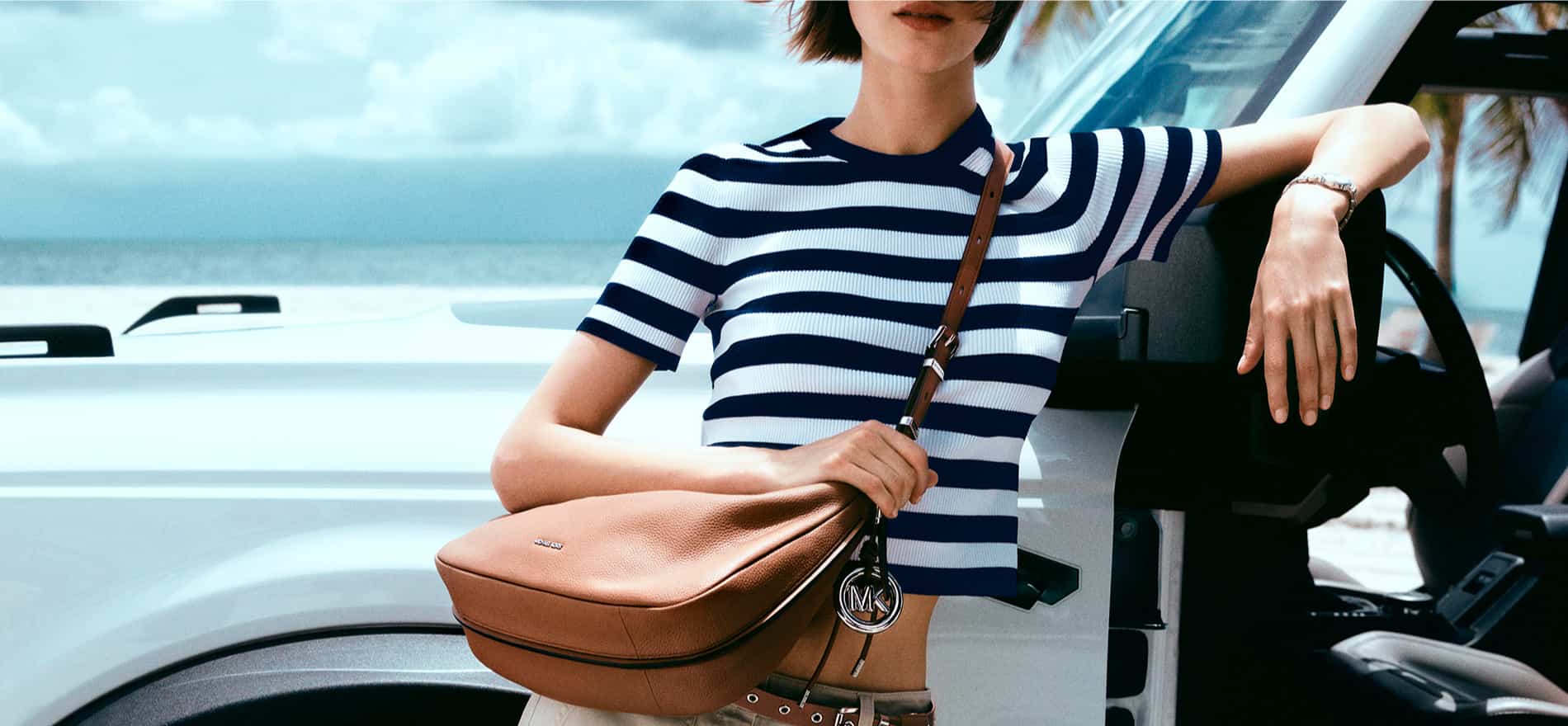 Mujer recargada en un auto usando playera a rayas blancas y azules