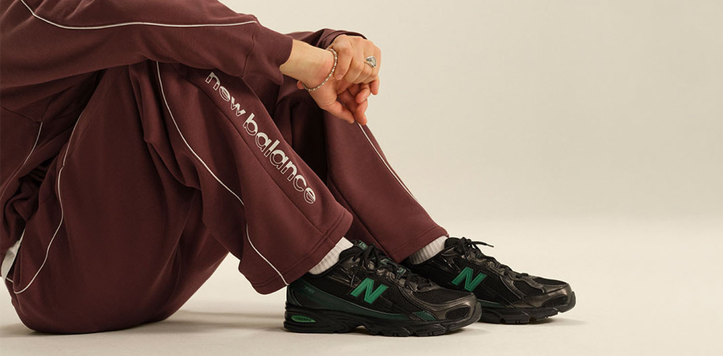 Hombre sentado usando pants color vino y tenis negros