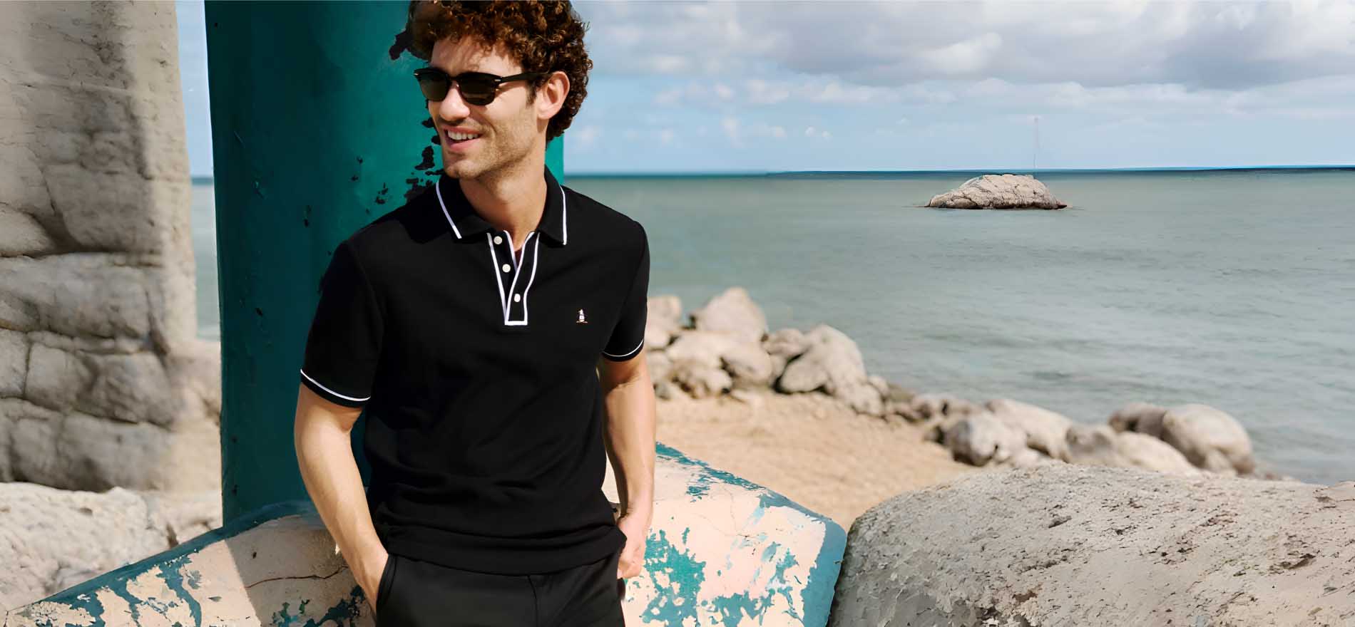 Hombre en una playa con ropa negra y lentes de sol negros