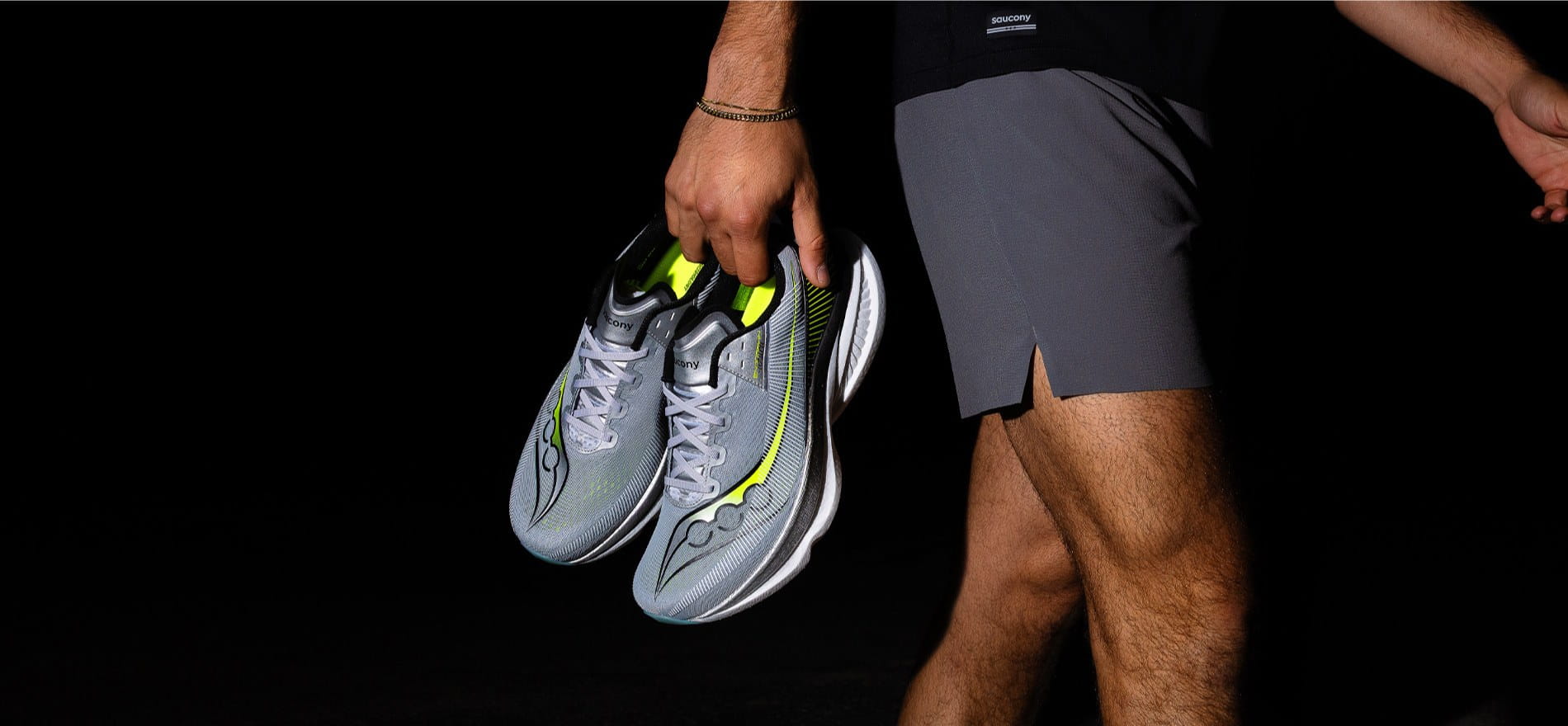 hombre cargando unos tenis color gris de la marca SAUCONY