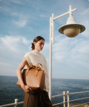 Imagen de mujer con bolso cafe de la marca ADOLFO DOMÍNGUEZ banner menu