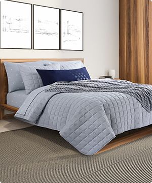 Imagen de una cama con sabanas almohadas y colcha de color gris de la marca ORIGINAL PENGUIN banner menu