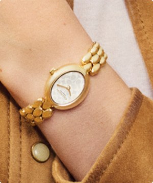 Imagen de un reloj color dorado de la marca COACH, banner menu