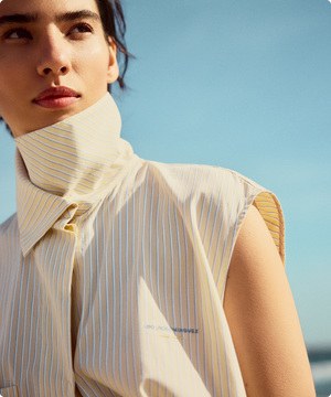 Imagen de una mujer usando blusa blanca de la marca ADOLFO DOMÍNGUEZ, banner menu