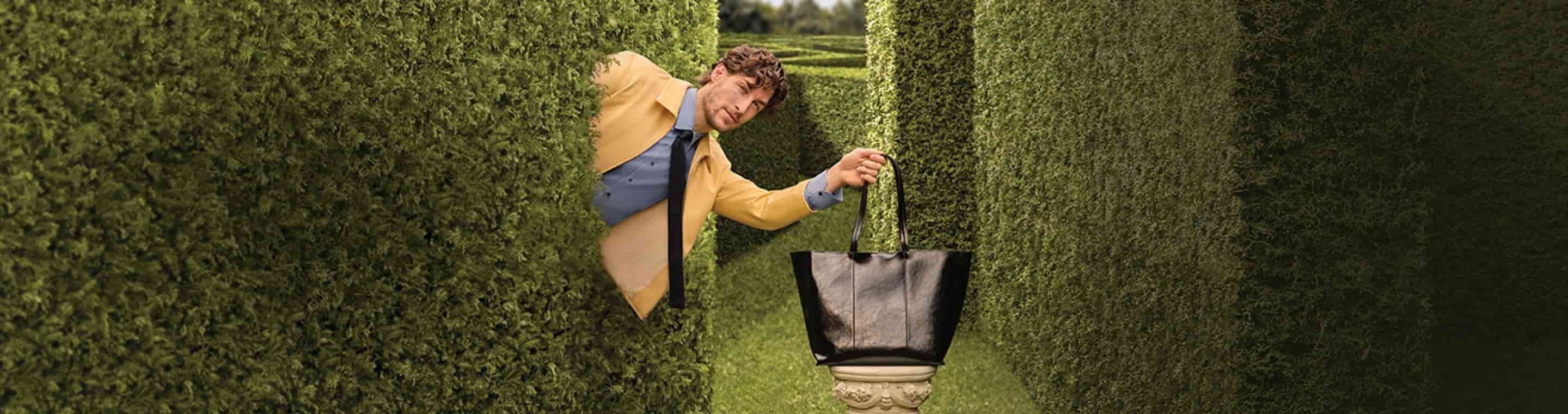  REBAJAS PERDETE EN ELLAS, imagen de de un hombre saliendo de unos arbustos para agarrar una bolsa color negrs, Hasta 40% de descuento + 3 m3nsualidades sin intereses de junio 22 a julio 16