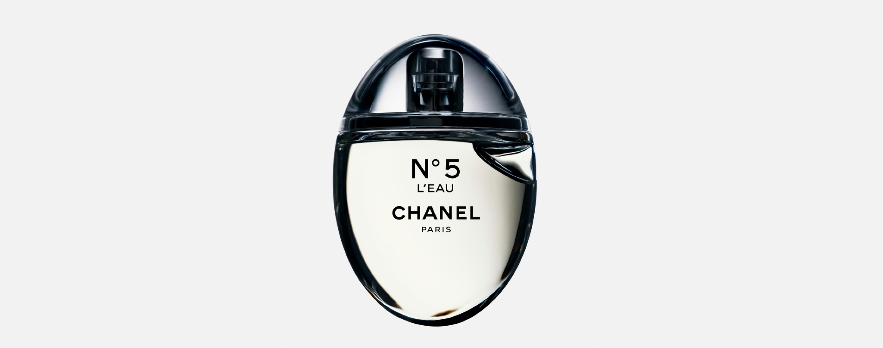 Mujer viendo al espectador, lleva blusa color negra, delante de ella un frasco de perfume Nº5 L'EAU CHANEL