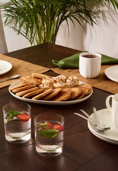 Imagen de un sillon color beige y una mesita de madera con dos tazas de cafe y un florero