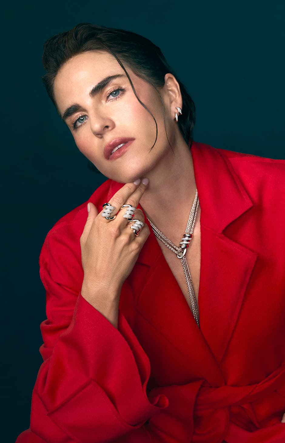 Mujer usando gabardina roja, anillos y collar plateado TANE