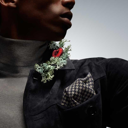 hombre con chamarra negra ensima de su chamarra unas cerezas y un racimo de chypre