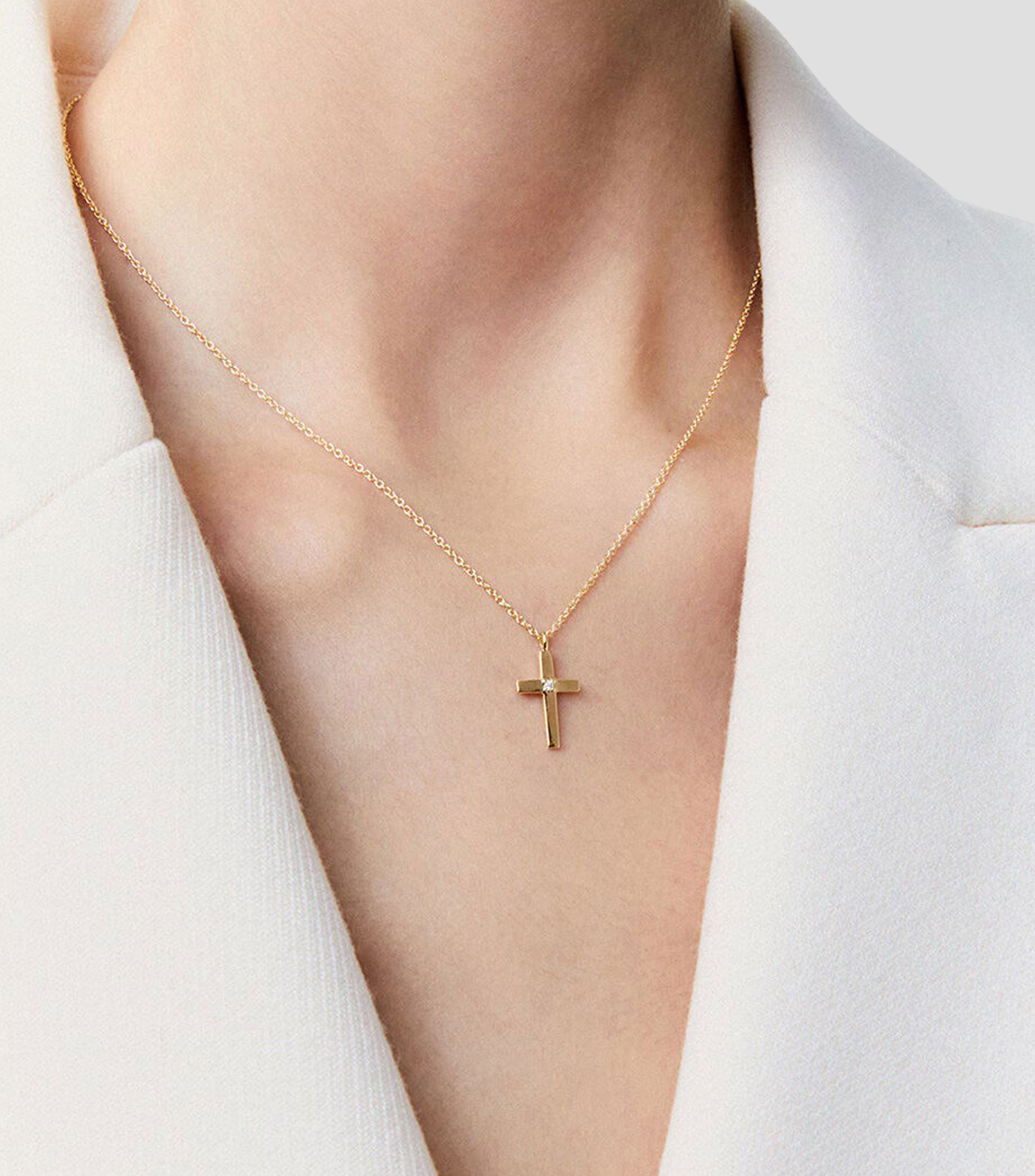 Colgante de oro amarillo de 18K con cruz mediana y diamante en talla brillante de 0,01 cts