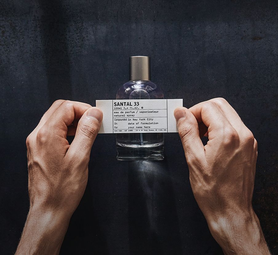 Imagen de una persona colocando etiqueta a un frasco de perfume de la marca LE LABO