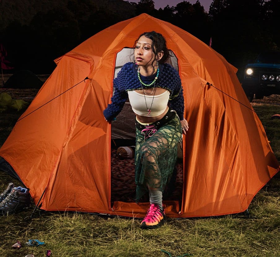 imagen de mujer saliendo de casa de campaña naranja de la marca MERRELL