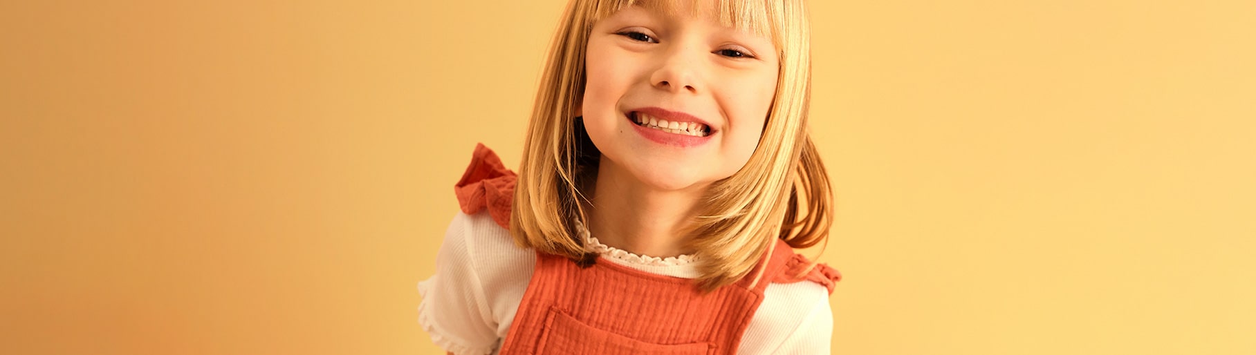 imagen de una niña usando blusa blanca y vestido color naranja de la marca BOBOLI 