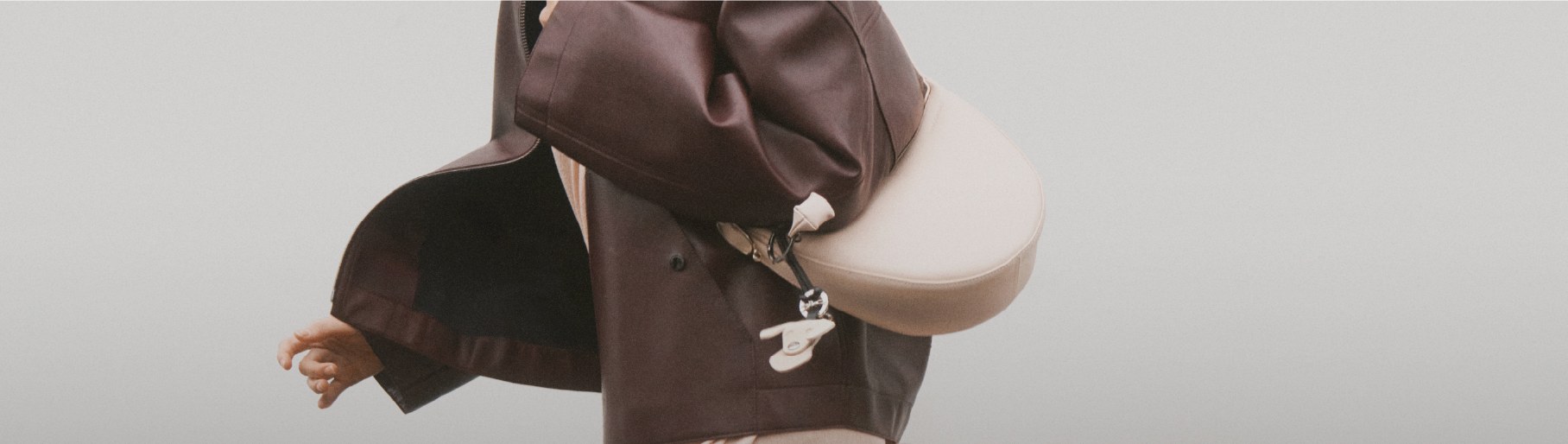 Imagen de una mujer con chamarra de pierl color cafe, lleva un bolso color blanco, Segmento Mujer, PLP Mujer