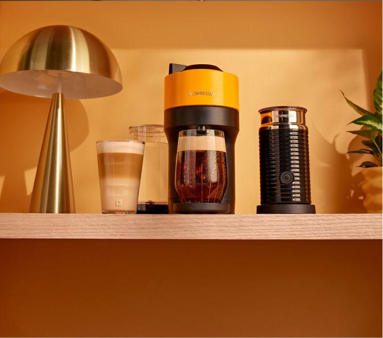 Imagen de una cafetera negra con una taza de capuccino, NESPRESSO