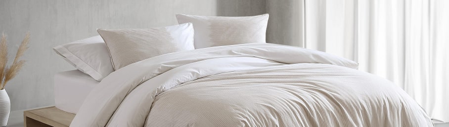 imagen de cama con edredon y almohadas blancas CAlVIN KLEIN HOGAR
