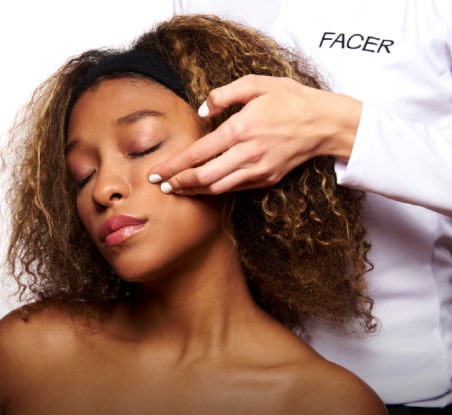 imagen de mujer con los ojos cerrados mientras le aplican tratamiento para la piel  en la mejilla, FACER 