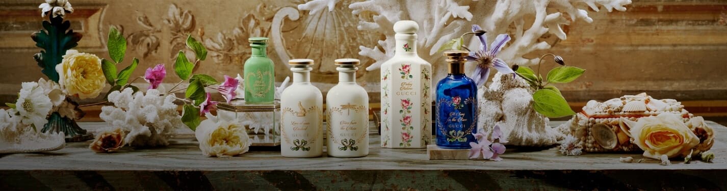 Imagen de cuatro frascos diferentes de la coleccion the alchemist garden de la marca GUCCI entre flores y corales, GUCCI