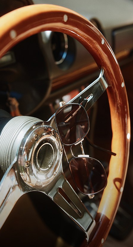 imagen de el volante de un automovil, colgando de el unos lentes de sol de la marca ALDO