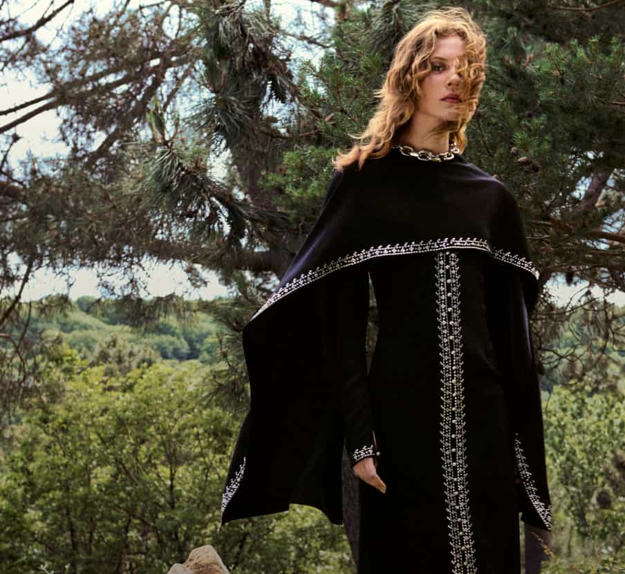 Imagen de mujer con vastido y capa negra con detalles blancos. RABANNE