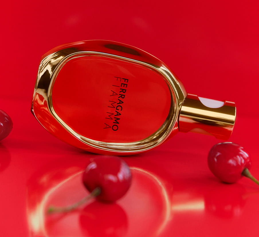 Imagen del fracos de perfume FIAMMA de la marca FERRAGAMO junto a ceresas rojas, FERRAGAMO