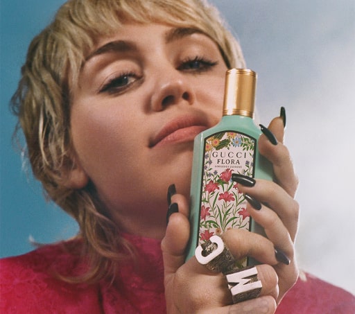 Mujer sostiene botella verde de perfume de la marca GUCCI floral gardenias. GUCCI