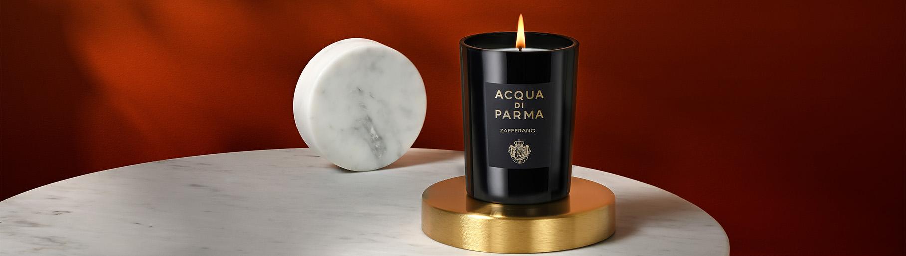 Imagen de una una mesa redonda de marmol en la cual se encuentra una vela redonda y vela con vso negro, ACQUA DI PARMA