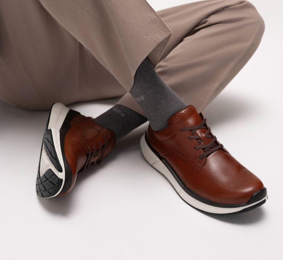 imagen de persona con par de zapatos cafes, ECCO Biom