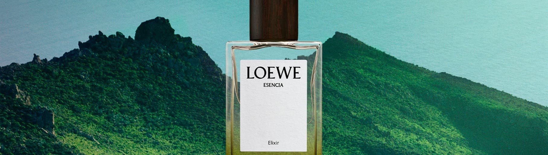 Imagen de un frasco de perfume de la marca LOEWE, de fondo dos montañas verdes