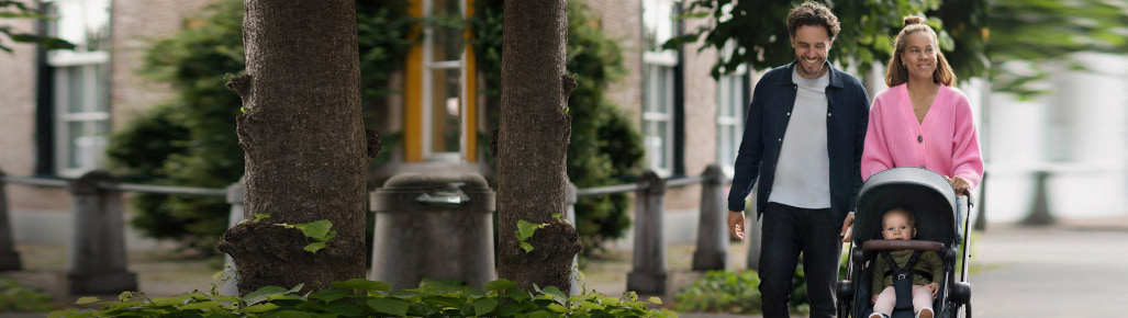 imagen de una mujer y un hombre caminando por la calle llevando una carriola