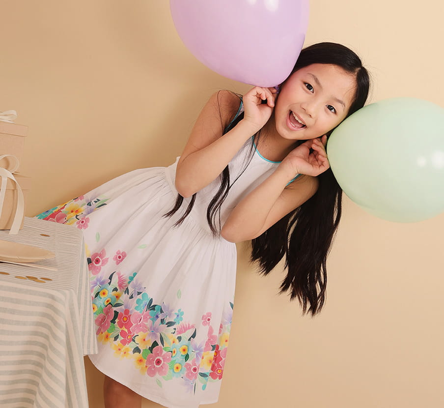 Imagen de una niña con vestido blanco que tiene estampado de flores en la parte baja de la marca BOBOLI